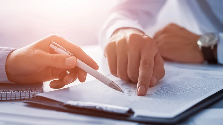 Zwei Personen zeigen auf ein Dokument und besprechen dieses.