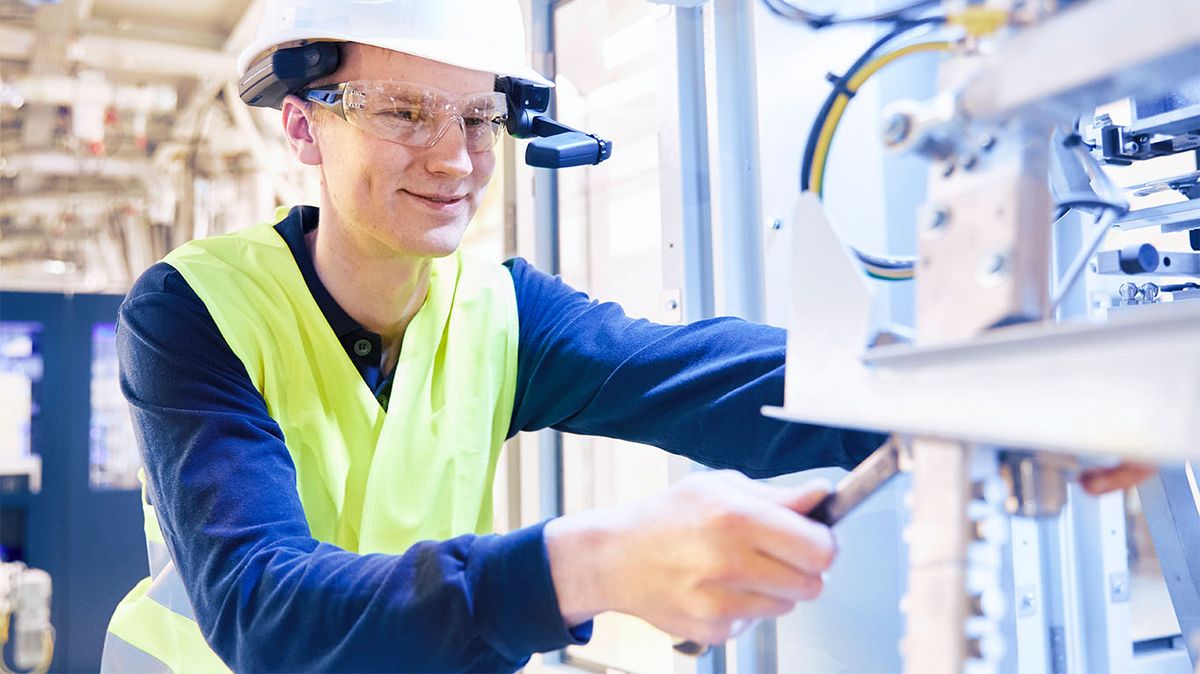 Ein Mann mit intelligenter Brille arbeitet an einer Maschine.
