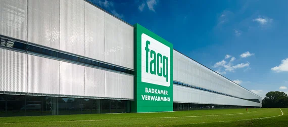 FACQ headquarters with a semi-transparent architectural mesh façade providing solar shading, surrounded by a green lawn.